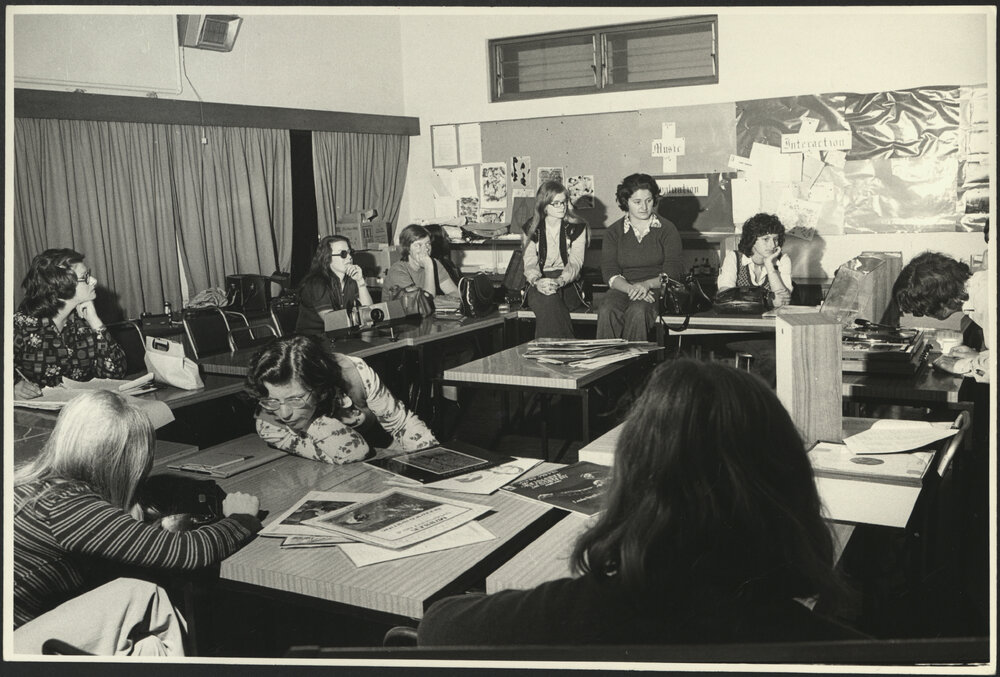 Nine Education Students in Class Room Sitting at and on Tables