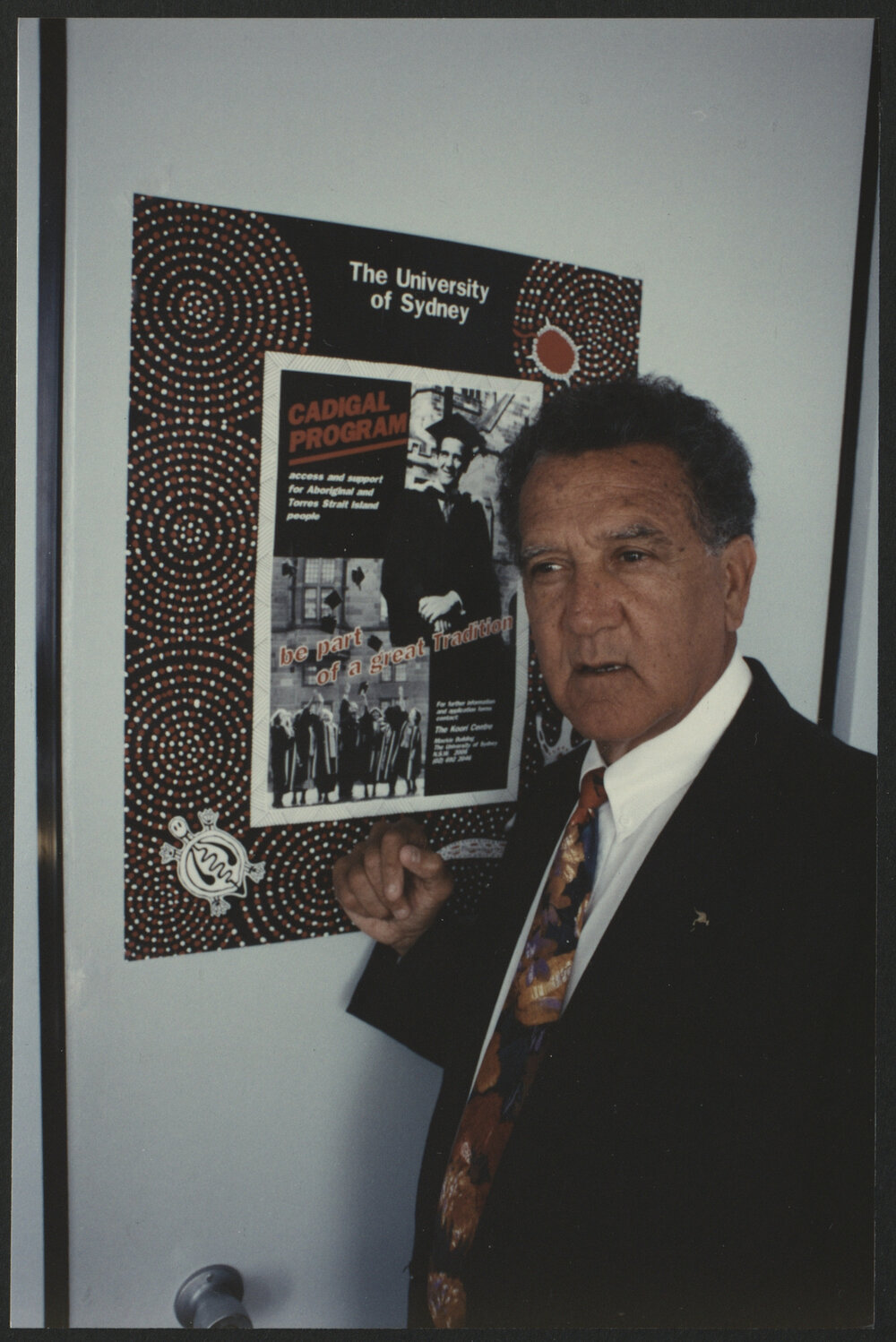 Charles Perkins in Front of a Poster Advertising the Cadigal Program