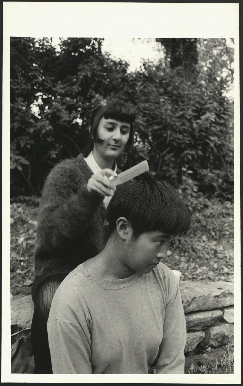 Outdoor Hairdressing - A Male Receives a Haircut by a Female Who Sits on a Wall Behind him