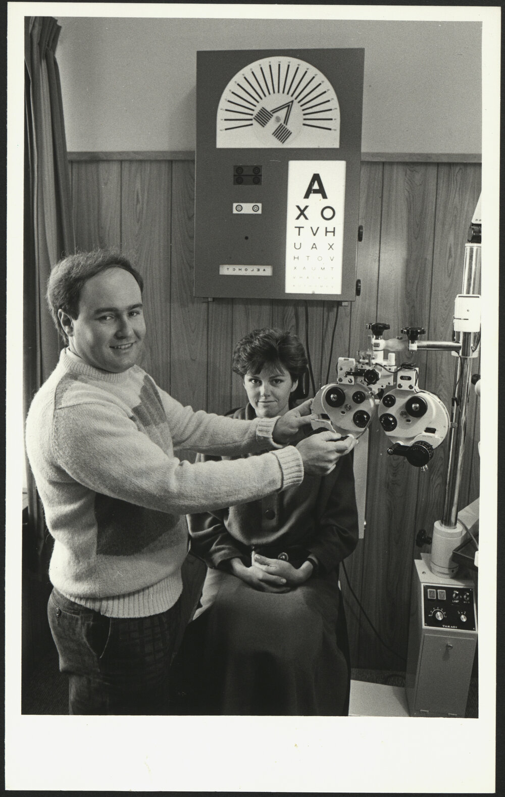 Chris McMahon University Optometrist Adjusting His Equipment  While a Patient Is Waiting in the Chair