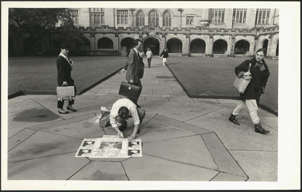 Students and Assoc/Prof Ian Jack Passing a Student Sticking Poster in the Centre of the Quad
