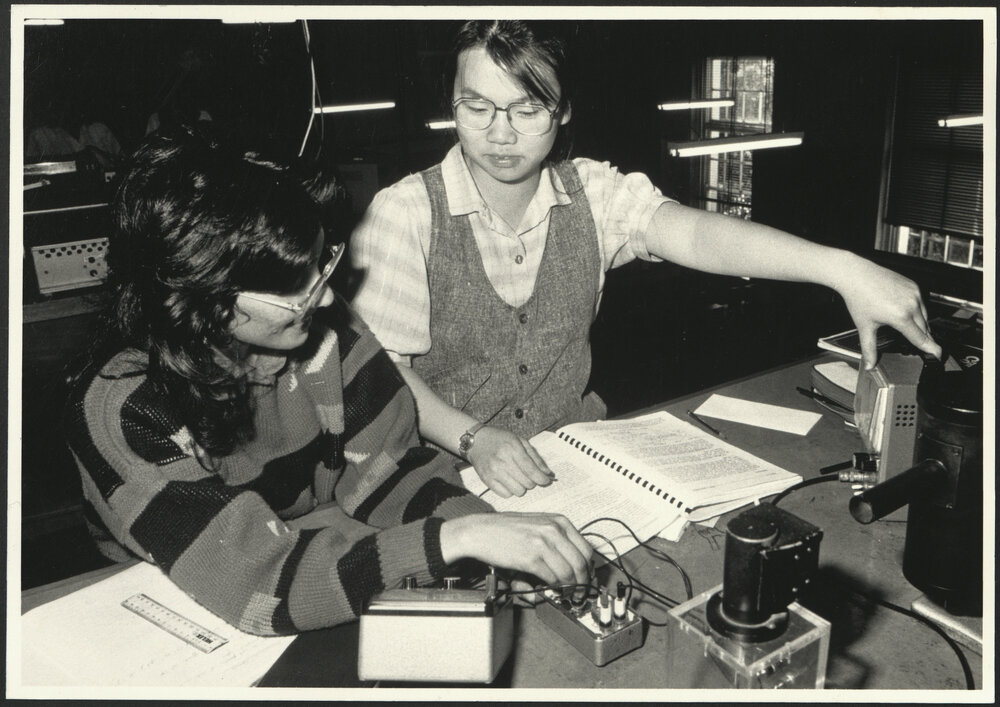 Physics Laboratory with Two Students Sitting at a Laboratory Desk Assessing an Experiment