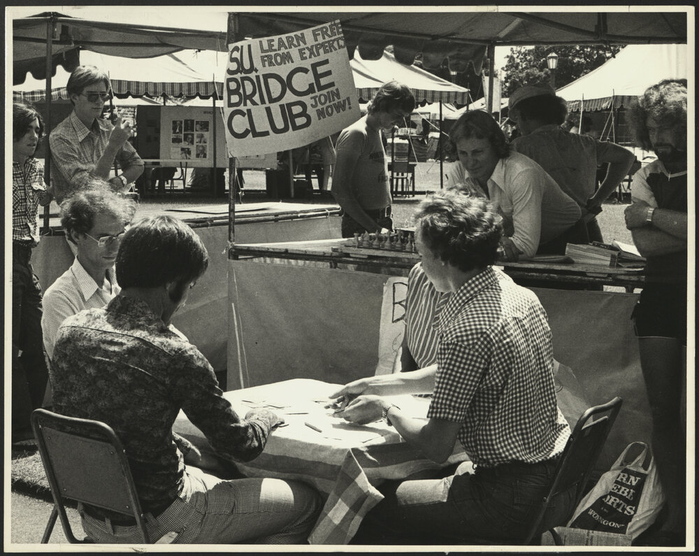 Four Students Play Bridge at a Table in Front of the SU Bridge Club Stall at Orientation Week