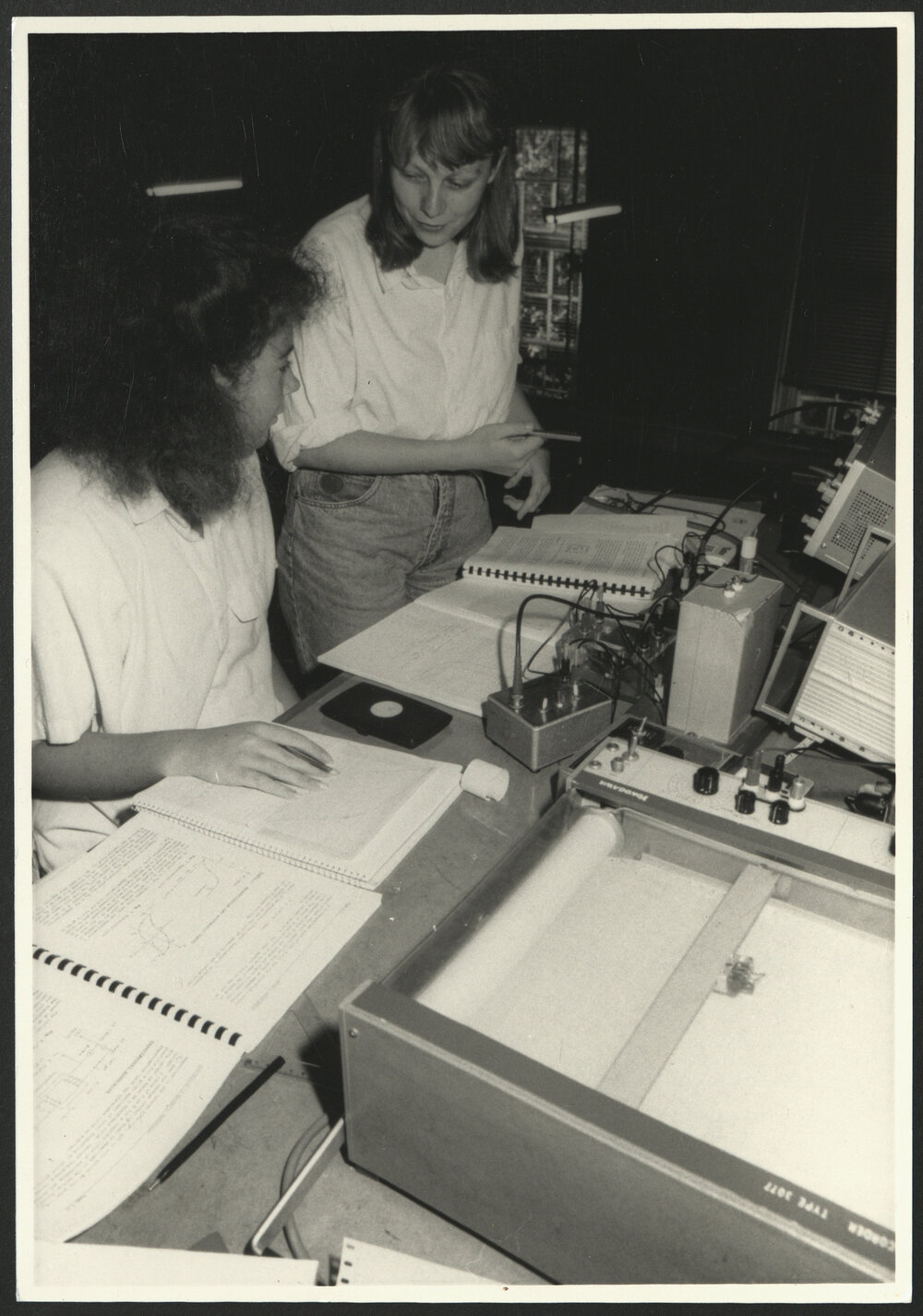 Physics Laboratory Two Students at a Desk Checking Papers