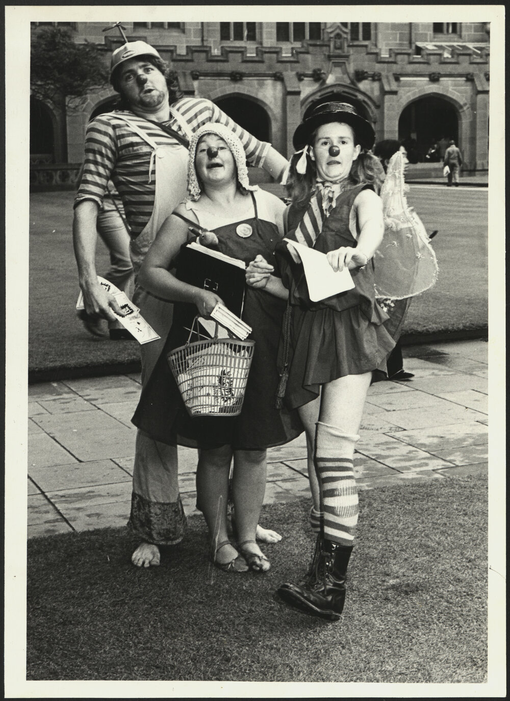 Three Students Dressed as Clowns Are Handing Out Leaflets for a Musical Performance During Orientation Week 