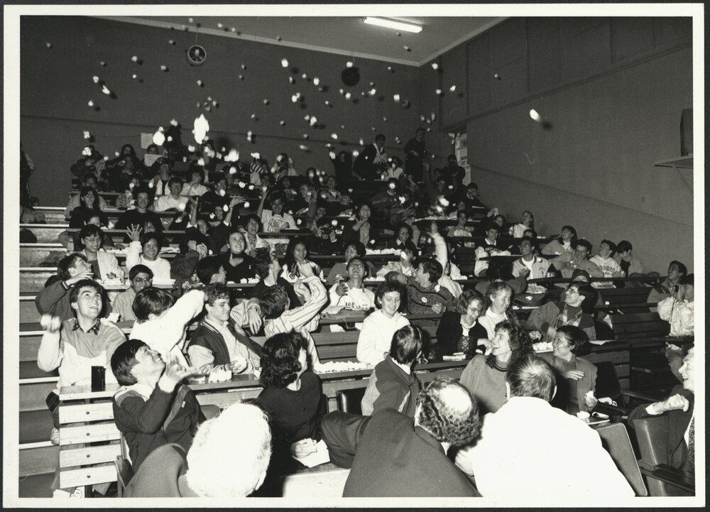 Students in Lecture Theatre Throwing Crumpled Paper Up into the Air