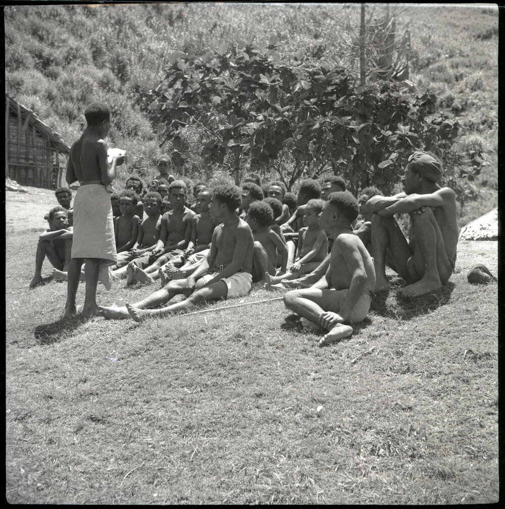 Group Seated Before Standing Man