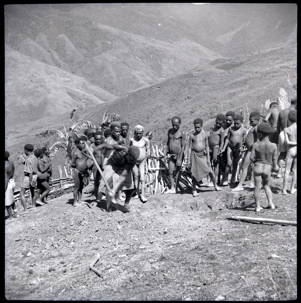 Man Digging With Shovel Before Group