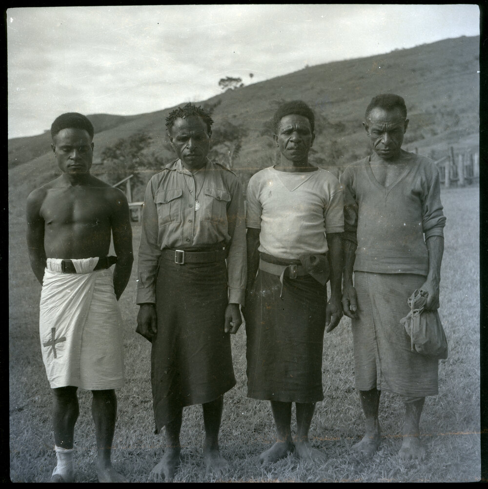 Four Men, One With Cross Sewn on Clothing