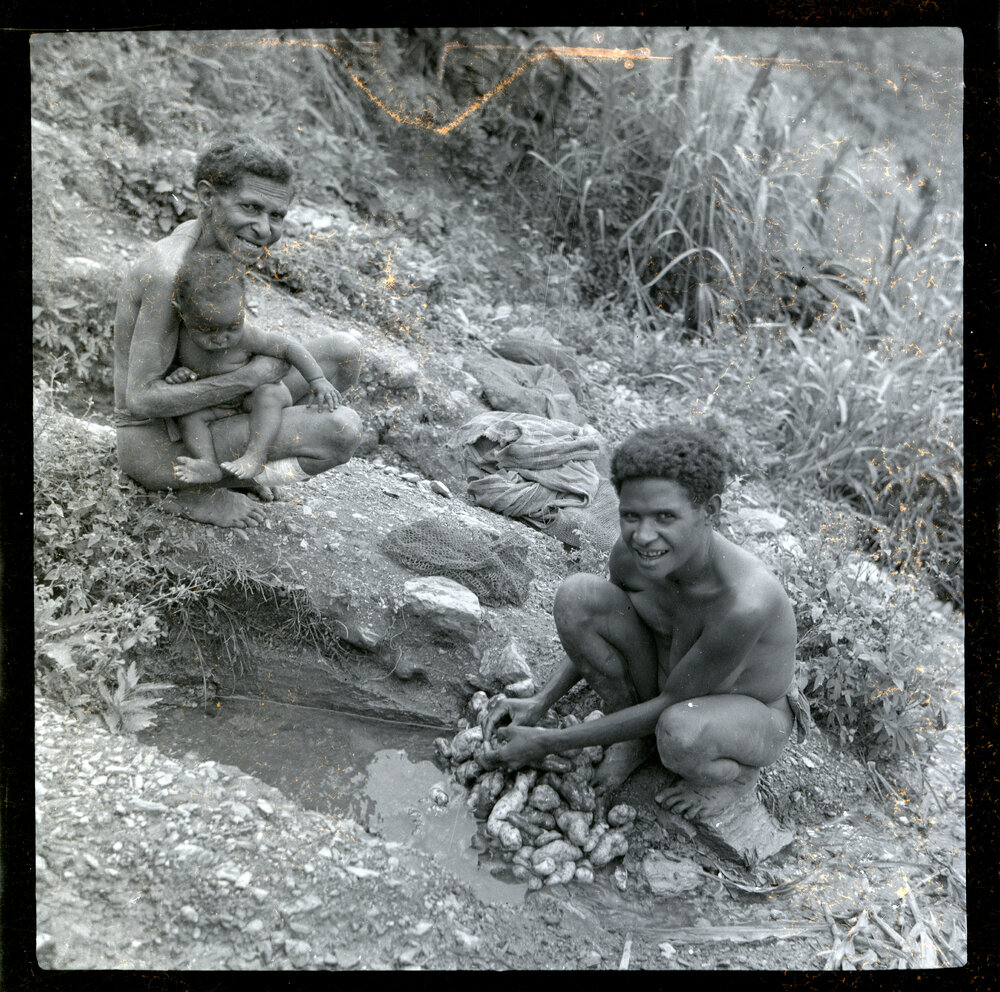 Woman Washing Vegetables While Another Sits with Child