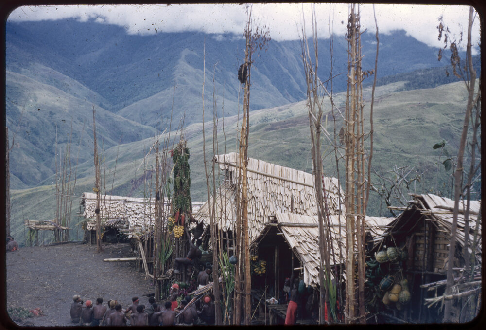 Group of Men Sitting at the Base of a Food Pole