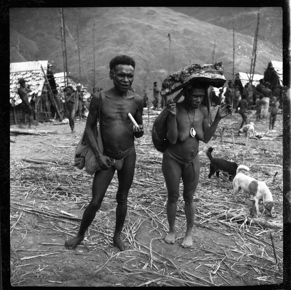 Man Standing with Woman Carrying Pork