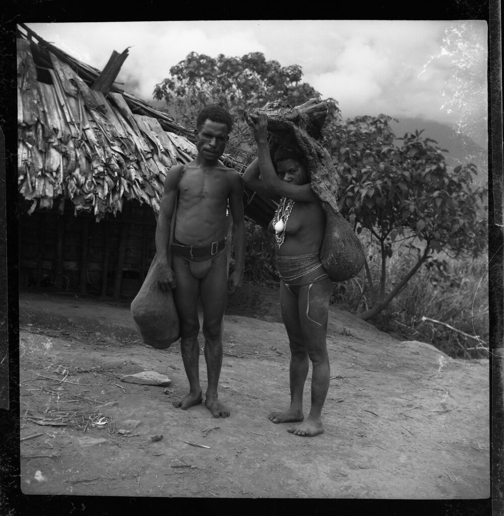Man Standing with Woman Carrying Pork