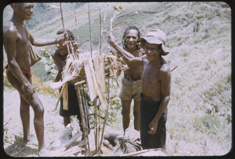 Men Standing Around a Stick Structure