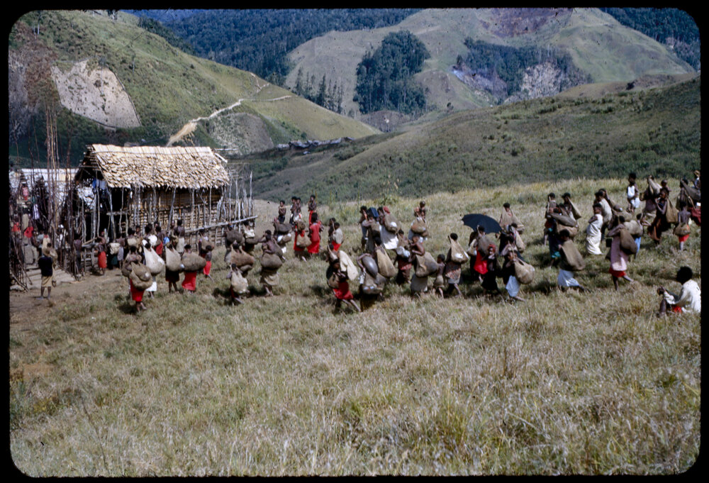 Crowd with Net Bags Walking Towards Village