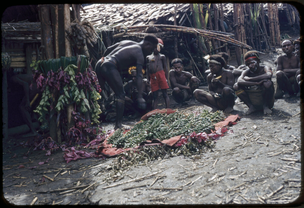 Group Sitting at the Base of a Food Pole