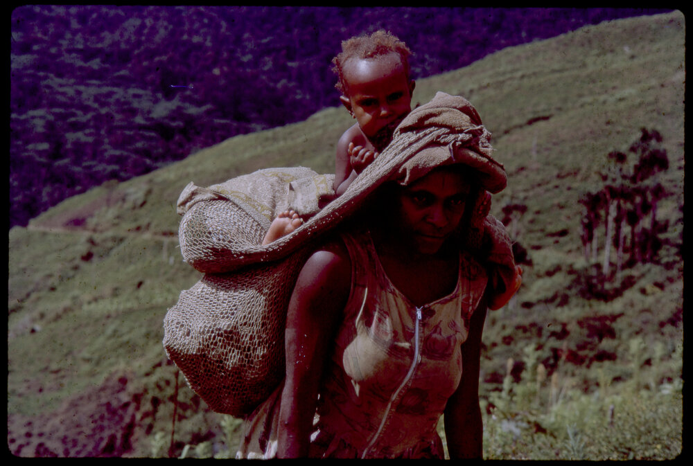 Woman Carrying Net Bags and a Child