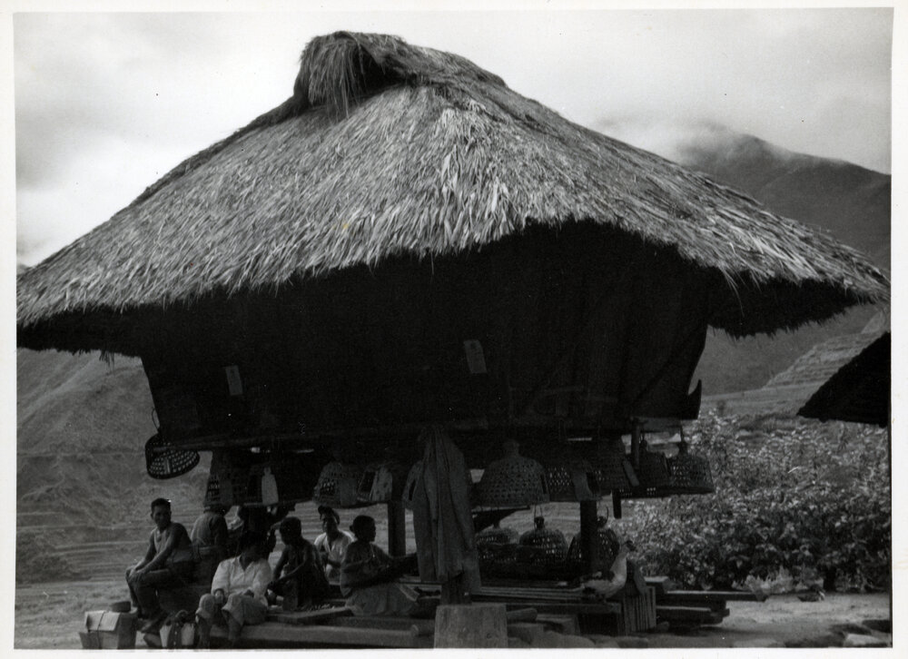 Group Sitting Beneath Wooden Structure on Stilts