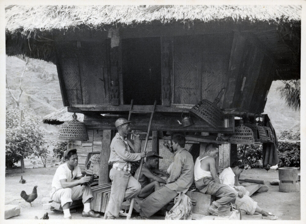 Group Sitting Beneath Wooden Structure on Stilts