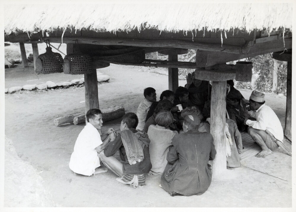 Group Sitting Beneath Wooden Structure on Stilts