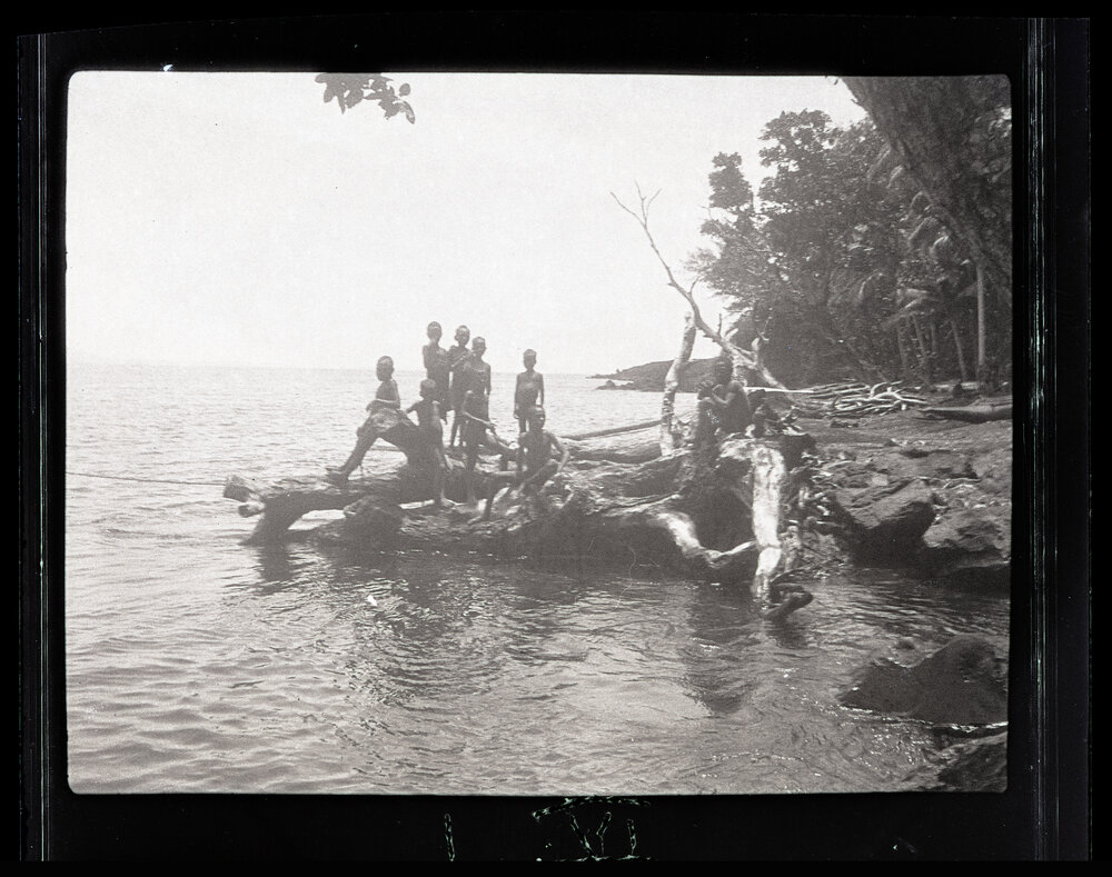 [Manum Island, New Guinea] Small Boys Play on the Shore While the Visitors Titivate Before Going up to the Village