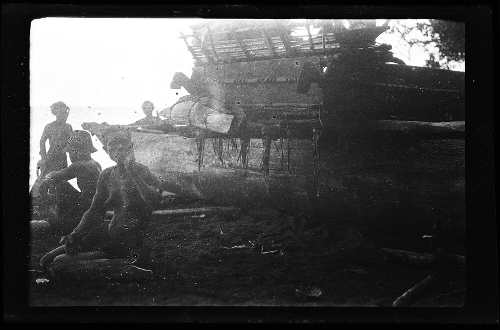 [Manum Island, New Guinea] The Blind Ona'a Waiting Beside the Canoe. Note the High Perapera of the Canoe with its Load