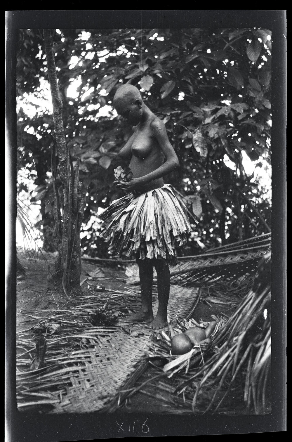 [Manum Island, New Guinea] Tsomoraua Annoints Herself with Special Leaves. The Baby is Lying on the Ground