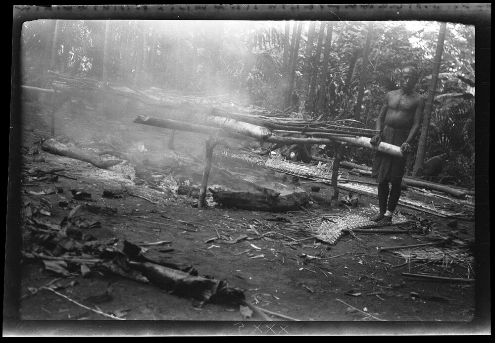 [Manum Island, New Guinea] The Beginning of the Cooking. Zeredo'i Standing Beside the 'Bed'