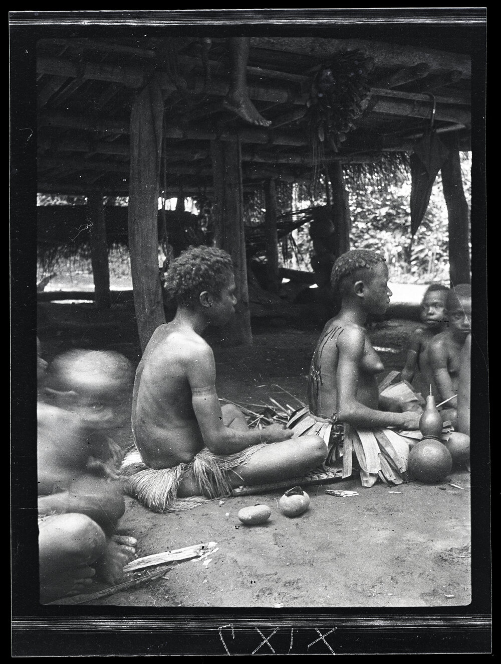 [Manum Island, New Guinea] A Woman Cutting Ornamental Scars on a Girl&rsquo;s Back During her First Menstruation Rites