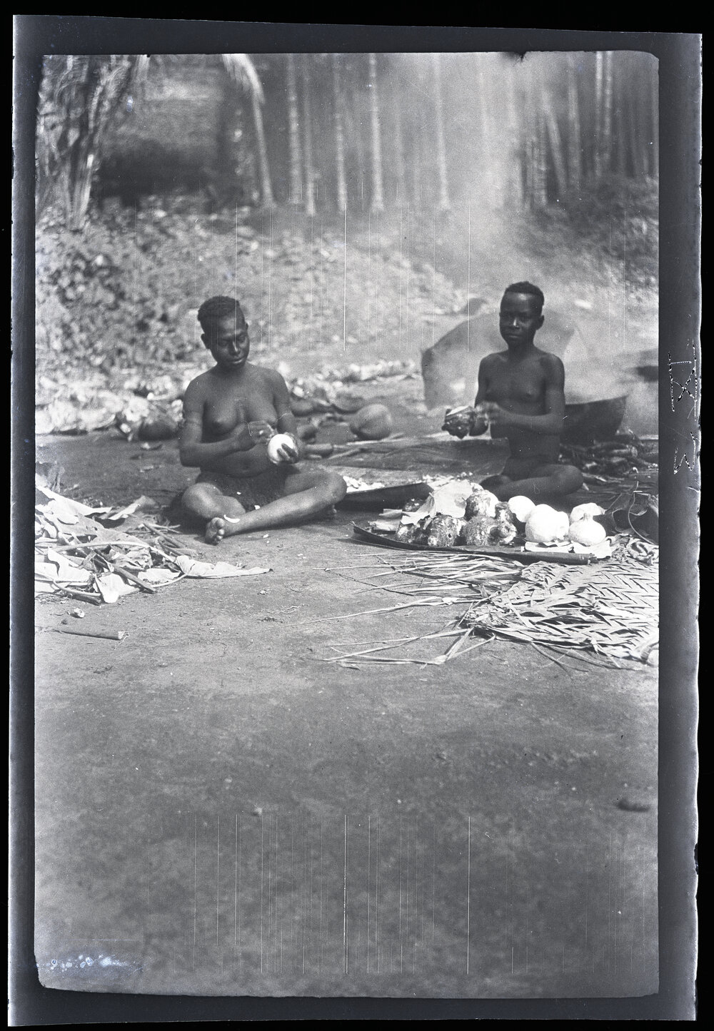 [Manum Island, New Guinea] Sagido and Kudsiri Scraping Taro (Brought by the Men of Yassa) and Cooking it