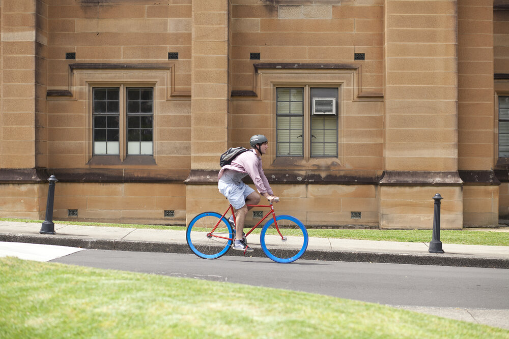 Student Biking Down Fisher Road, View of Anderson Stuart Building