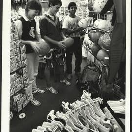 Three Students Checking Out Balls in the  Sports Store of the Sports Union