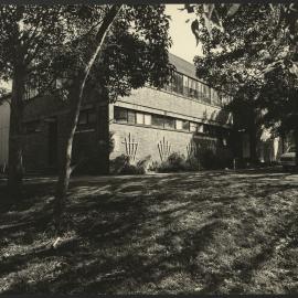 View Across Green to HK Ward Gymnasium Building with Cars Parked Across from the Entrance