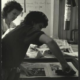 Two Participants in Action Using Newspapers at a Printing Workshop