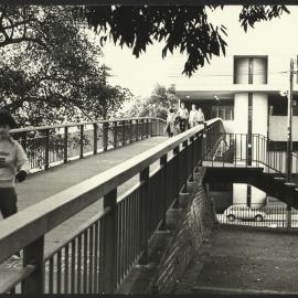View from Campus Across the Footbridge Towards Wentworth Building with Students Crossing the Bridge