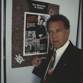 Charles Perkins in Front of a Poster Advertising the Cadigal Program