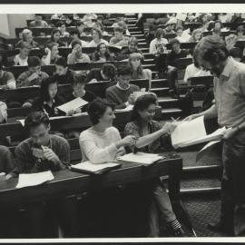 Students in Lecture Room with Lecturer Handing Out Papers