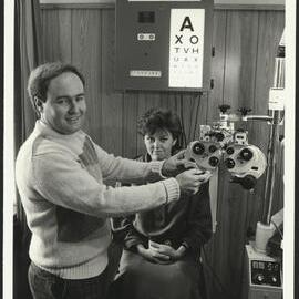 Chris McMahon University Optometrist Adjusting His Equipment  While a Patient Is Waiting in the Chair