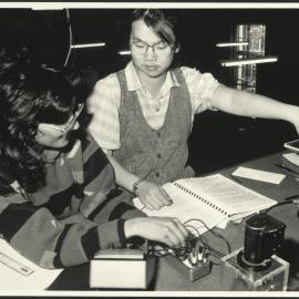 Physics Laboratory with Two Students Sitting at a Laboratory Desk Assessing an Experiment