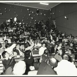 Students in Lecture Theatre Throwing Crumpled Paper Up into the Air