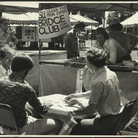 Four Students Play Bridge at a Table in Front of the SU Bridge Club Stall at Orientation Week