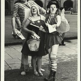 Three Students Dressed as Clowns Are Handing Out Leaflets for a Musical Performance During Orientation Week 