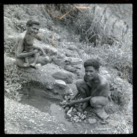 Woman Washing Vegetables While Another Sits with Child
