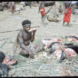 Man Eating Beside Butchered Pigs