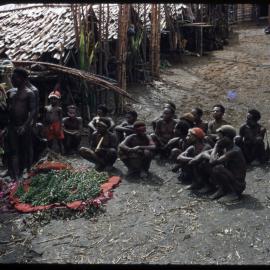 Group of Men Sitting at the Base of a Food Pole