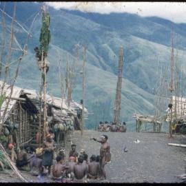 Group of Men Sitting at the Base of a Food Pole