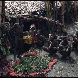Group of Men Sitting at the Base of a Food Pole