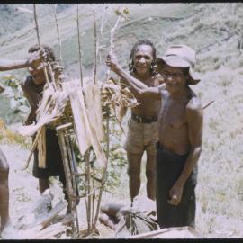 Men Standing Around a Stick Structure