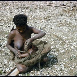 Woman Placing Child in Net Carrier