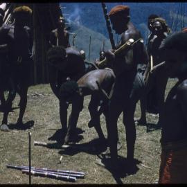 Men Placing Down Sticks to Determine Food Piles